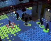 450 m2 Massive interactive floor about Epidemics.n80 players at the same timenEach player who enter the game zone gets an “aura” around him which give him information about his health and status. The player must survive an epidemic, following instructions given by the front screen and the sound, he interact with the environment on the interactive floor to survive the epidemic.nt5 differents scenarios, around 22 minutes eachnt31 Video Projectors for floor projectionnt6 Video Projectors for wa