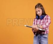 Get 100&#39;s of FREE Video Templates, Music, Footage and More at Motion Array: http://bit.ly/2SITwWM nnnGet this here: https://motionarray.com/stock-video/girl-with-laptop-152516nnThis stock footage features a girl with a laptop in her arms and a pair of wireless headphones around her neck. She is shot over an orange background in a studio. Use this clip in vlogs, social media posts, web adds or tv commercials related to youth, young girl and technology, school, studying etc. There is copy-space av
