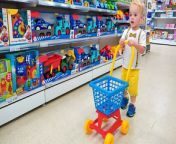 Kid Chris with mom doing shopping in Toy store. A child at the supermarket with a shopping cart buys a lot of toys